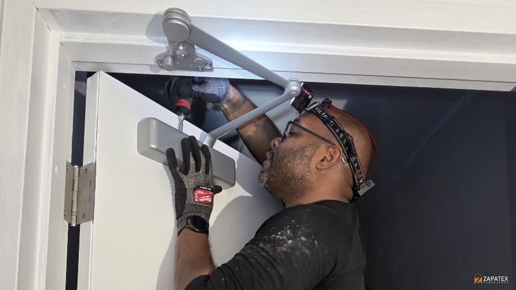Tecnico de Zapatex durante la instalacion de door closer, ajustando el brazo sobre la puerta